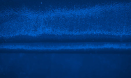A deep blue background with a glossy finish, showing a smooth texture and subtle shine. This rich blue hue creates a dynamic and vibrant surface, ideal for abstract or artistic projects.の写真素材