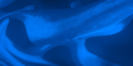 Abstract photography of blue fabric focusing on its intricate surface texture and subtle lighting variations. The fabric's curves and soft folds create a calming visual aesthetic.の写真素材
