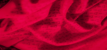 A bright red fabric with a repeating black stirrup pattern, captured in a mid-range shot. The intricate details of the design and subtle fabric folds create a visually appealing composition.の写真素材