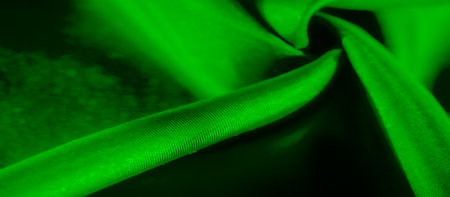 A beautifully abstract image of smooth green fabric in dynamic folds. The image captures light reflections, enhancing the silky texture, perfect for fashion or design-related purposes.の写真素材