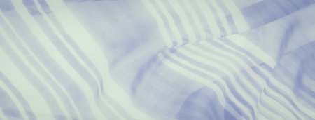 A folded fabric with varying stripe widths, creating a gentle wave effect. The translucent texture allows light to play through, enhancing the soft pastel color scheme of blue and white.の写真素材