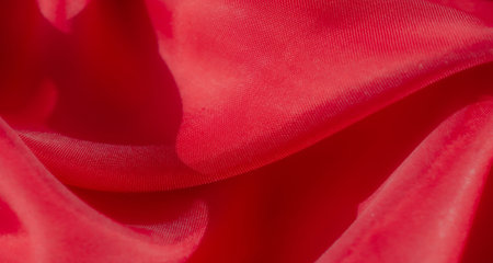 An abstract close-up of red fabric, with vibrant color and intricate folds The satin material reflects light beautifully, adding depth to the texture. The dynamic arrangement gives it a luxurious feelの写真素材