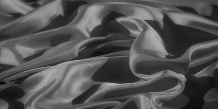 This abstract photograph focuses on the wavy folds of fabric illuminated by natural light. The fabric's silky texture is enhanced by the high contrast between the light and shadows,の写真素材