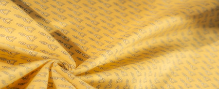 A detailed close-up of yellow fabric with a repeating black stirrup pattern. The flowing textile...