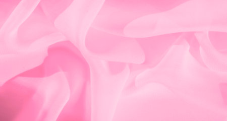 Blurred soft pink fabric with subtle flowing folds creates a delicate, dreamy texture. The fabric's translucent nature adds an airy and ethereal quality, ideal for creative projects.の写真素材