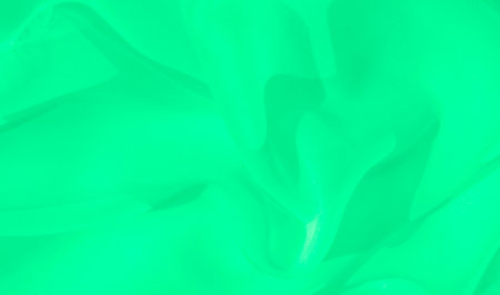 Blurred green fabric with smooth folds and curves creates a tranquil, flowing effect. The soft texture and minimalistic design contribute to the image's modern and serene aesthetic.の写真素材