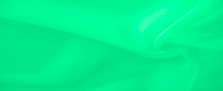 Blurred green fabric image highlighting smooth and fluid folds with a soft gradient, creating a minimalist and abstract composition. The light shadows add depth and tranquility to the design.の写真素材