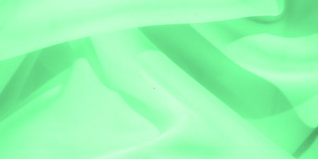 Blurred abstract view of green fabric in soft, fluid waves creating a dynamic and organic composition. The vibrant green hue amplifies the motion and texture of the fabric, giving it a lively presenceの写真素材