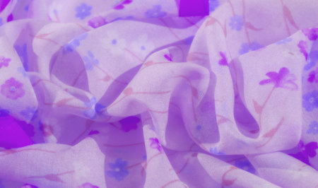 Blurred purple fabric with soft floral designs, flowing in smooth, elegant folds. The delicate chiffon material creates a dreamy texture, enhancing the romantic and feminine aesthetic.の写真素材