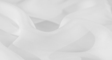 Blurred white fabric with flowing folds and a smooth, seamless texture. The soft design exudes minimalism and elegance, with subtle light enhancing its clean and pure aesthetic.の写真素材
