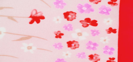 Blurred pastel pink fabric featuring a lovely blend of red, purple, and white flowers. The small floral details are balanced by soft beige stems, giving the fabric an airy and elegant feel.の写真素材
