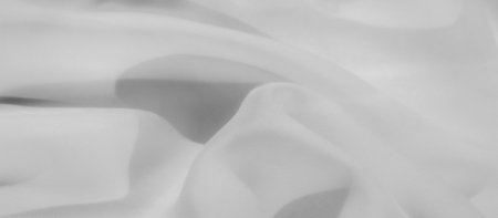 Blurred white fabric with gentle folds and soft texture conveys a sense of elegance and sophistication. The minimalistic design and light tones create a peaceful and refined background.の写真素材