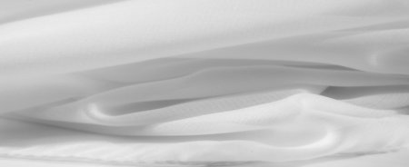 Blurred white fabric with soft, flowing lines creates a serene, minimalistic atmosphere. The subtle folds and smooth surface provide an abstract background perfect for elegant designs.の写真素材