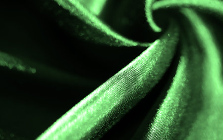 Blur. Smooth and luxurious green satin fabric featuring intricate folds and reflective light. The rich texture creates a flowing and elegant pattern, perfect for high-end fashion designsの写真素材