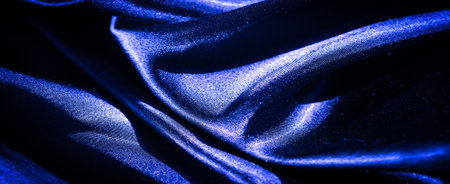 Blur soft waves of blue satin are highlighted, the shimmering surface rippling like liquid, creating a delicate balance between light and dark areas, enhancing its refined beautyの写真素材