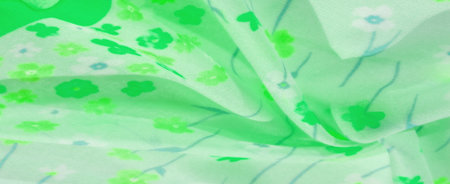 Blur of soft, pastel green fabric with a charming floral design in various green tones. The wavy folds and flowing texture give the fabric a soothing nature-inspired feel ideal for decorative projectsの写真素材