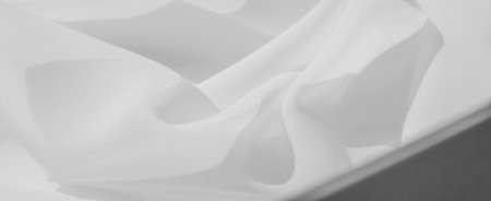 Blurred soft white fabric with smooth curves and delicate folds. The clean, minimalistic presentation offers a serene and modern aesthetic, ideal for backgrounds or design elements.の写真素材