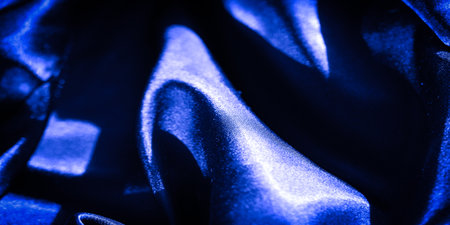 Blur of luxurious deep blue satin fabric flowing in smooth curves and folds, capturing the essence of elegance and shine. The silky texture reflects light in a subtle manner, creating a richの写真素材