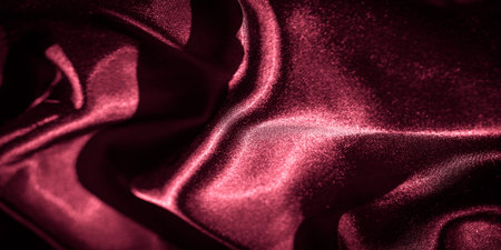Blur of dark red satin fabric with dramatic lighting emphasizing the fabric's luxurious texture and folds. The soft, flowing appearance creates a sense of sophistication and style.の写真素材