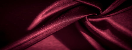 Blurred crimson satin fabric with deep folds and light reflections, offering a sumptuous, velvety texture. Ideal for premium textile backgrounds, interior decor, or fashion photographyの写真素材
