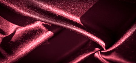 Blur of rich red satin fabric with deep folds and smooth, shiny surface, reflecting light to create a glossy and luxurious texture. Perfect for fashion, design, or abstract backgrounds.の写真素材