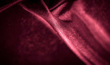 Blurred rich red satin fabric draped elegantly with shimmering light accents, creating a soft, flowing texture. Perfect for premium backgrounds, textile design, or fashion editorial projects.の写真素材