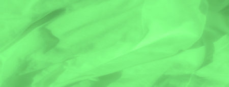 Blurred layers of green satin fabric form an abstract arrangement, capturing the fluid movement of the textile. The soft, silky surface reflects light gently, creating an impression of serenity.の写真素材