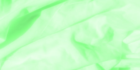 Blur of a smooth green fabric with soft creases. Light diffuses across the material, casting soft shadows and highlighting the fluidity and organic feel of the textile.の写真素材