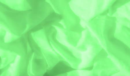 Blur of green satin fabric, with soft, gentle folds cascading across the surface. The luminous green color and smooth texture of the material add an ethereal and artistic quality to the fabric design.の写真素材