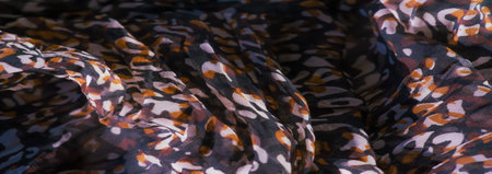 Blur of soft fabric with intricate red, black, and white abstract patterns. The design appears...
