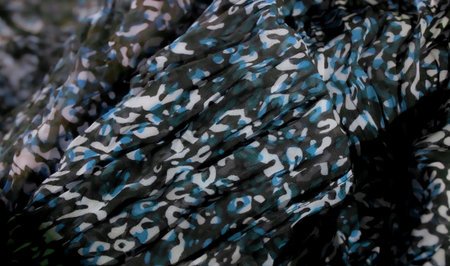 Blur of soft, flowing fabric featuring a camouflage pattern with blue, white, and green tones. The abstract pattern creates a visual texture that is both modern and dynamic, perfect for backgrounds or textile design themes.の写真素材