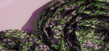 Blur of green, black, and white abstract patterns on a sheer fabric. The dynamic arrangement of...