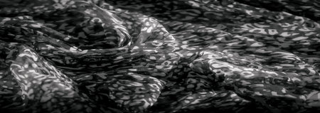 Blur of soft grayscale fabric with abstract patterns in light and dark tones. The folds and gentle...