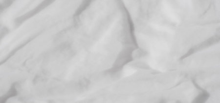 Blur of soft, white fabric with flowing wrinkles and gentle curves, offering an abstract and calming visual ideal for textile-themed projects or background usage.の写真素材