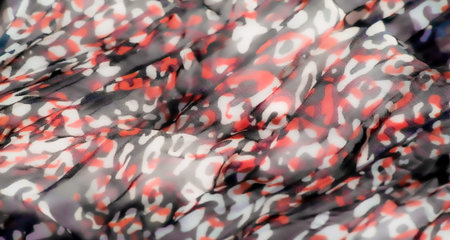 Blur of a sheer fabric with abstract, irregular patterns in shades of red, purple, and black. The...
