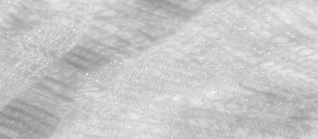 Blur of fine white lace fabric with shimmering details, creating an elegant, light-dappled effect....