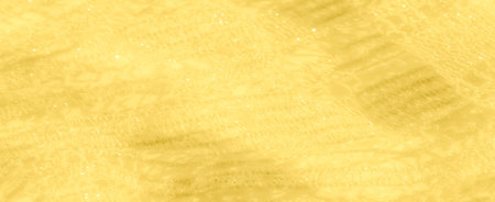 Blurred macro shot of yellow lace fabric with shimmering details. The light sparkles off the...