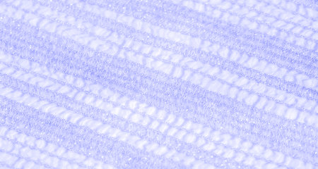 Blur of shimmering blue lace fabric with intricate designs and glittering details. The soft texture...