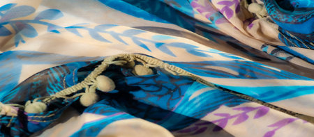 Blur of a vibrant blue and beige fabric with flowing textures and abstract patterns. The fabric's swirling folds create a dynamic visual with hints of purple and teal accents.の写真素材
