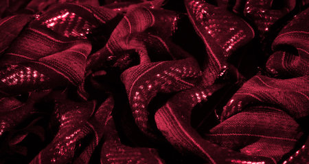 Blur of luxurious red fabric with deep textures and sparkling highlights. The dynamic folds and glowing elements create a visually striking and elegant design for fashion or home decor inspirations.の写真素材