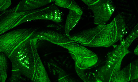 Blur the vibrant green fabric, illuminated by glowing fibers woven into abstract patterns. The intricate interplay of light creates a dynamic design, filled with rich texture and glowing details.の写真素材