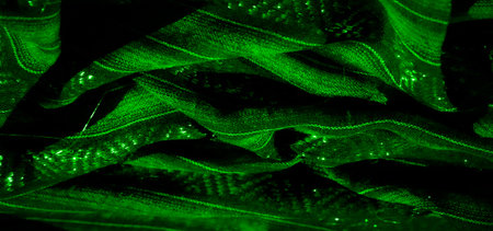 Blur: Deep green fabric with mesmerizing shimmering patterns. The intricate designs are accentuated by lighting, giving it an abstract and luxurious feel, highlighted by glowing textures.の写真素材