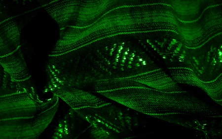 Blur: Textured green fabric with luminous highlights and intricate weaving. The folds and shimmer form an abstract, flowing design, creating a dynamic, glowing appearance.の写真素材