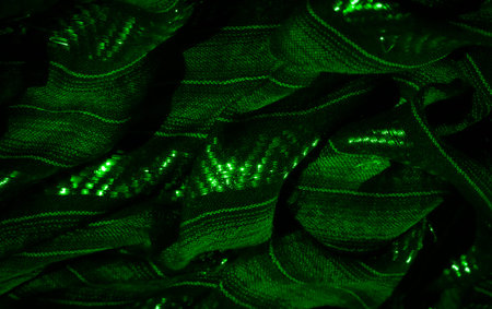 Blur of a green fabric with intricate textures and glowing highlights. The composition focuses on...