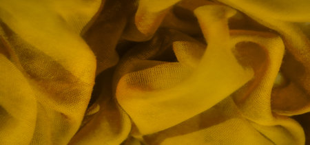 Blurred view of yellow fabric tightly spiraled, showing its fine texture and soft translucency. The...