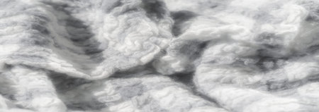 Blurred textured grayscale and white fabric with soft, detailed knitting. The image highlights the...