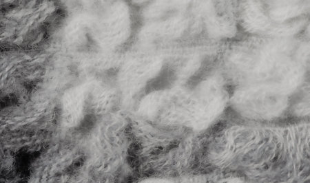Blurred soft white and gray wool fibers woven together to create a fluffy, cozy fabric. The close-up...