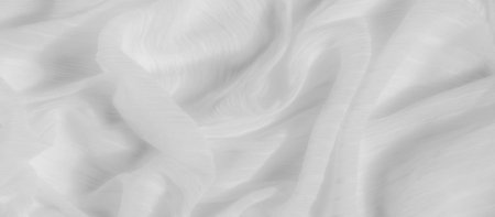 Blurred fabric displaying soft undulations and subtle patterns in a light monochromatic tone. The...