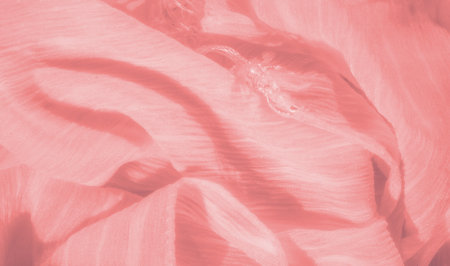 Blur of soft peach-colored fabric with flowing waves and delicate fibers. The material's smooth texture and gentle sheen provide a calming visual effect with a warm and inviting tone.の写真素材