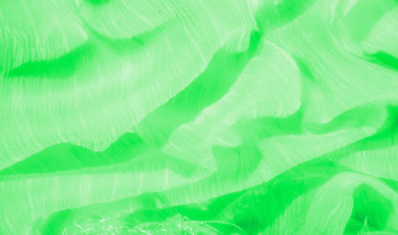 Blurred soft waves of neon green fabric creating an abstract and seamless pattern with subtle light reflections. The flowing texture and glowing tones offer a refreshing and energetic aesthetic.の写真素材